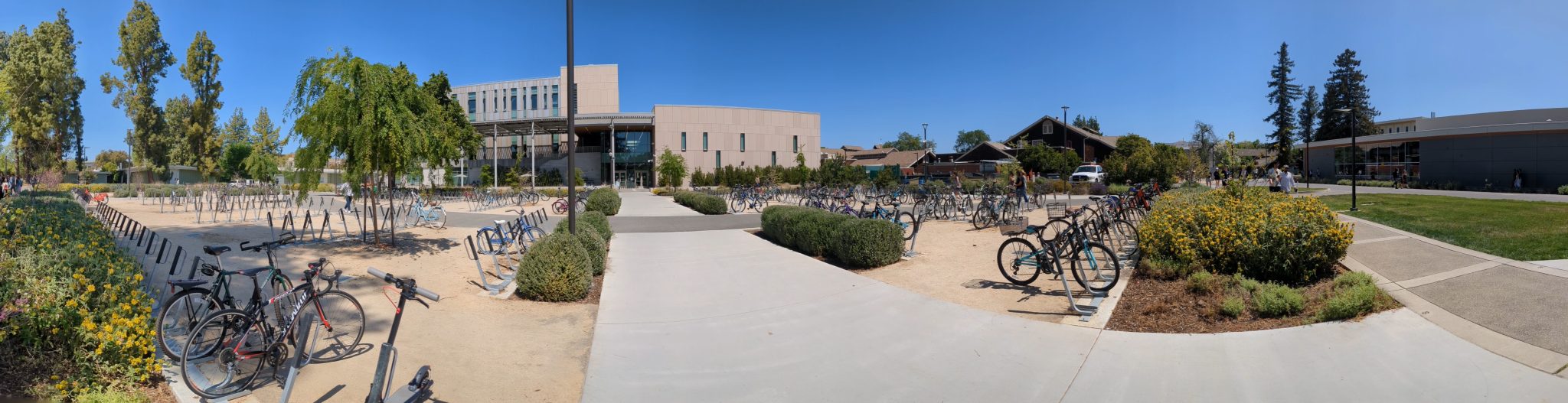 Bike parking lot in front of concrete building with a walkway down the middle.
