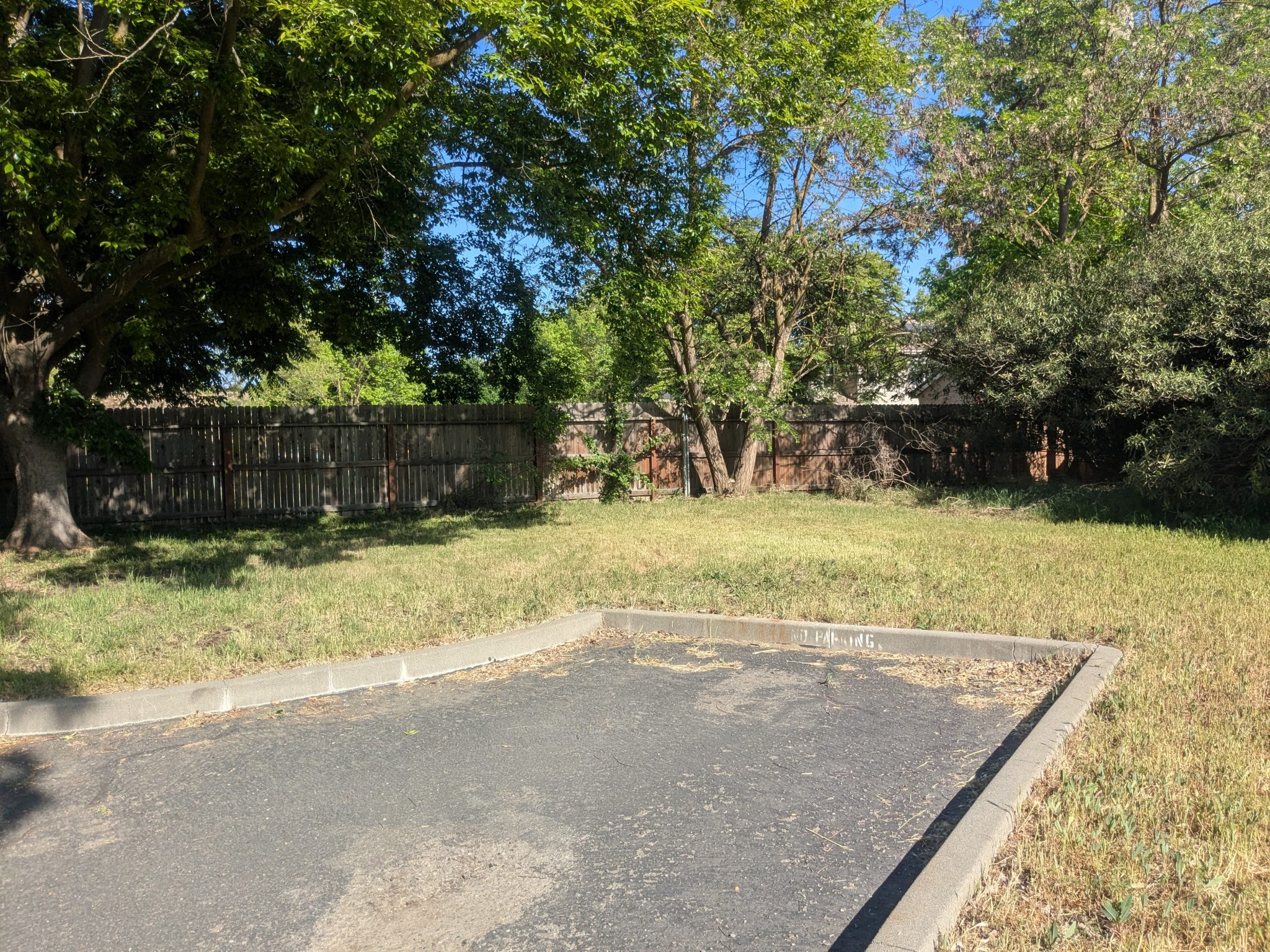 Cut off driveway surrounded by grass and a fence in the background