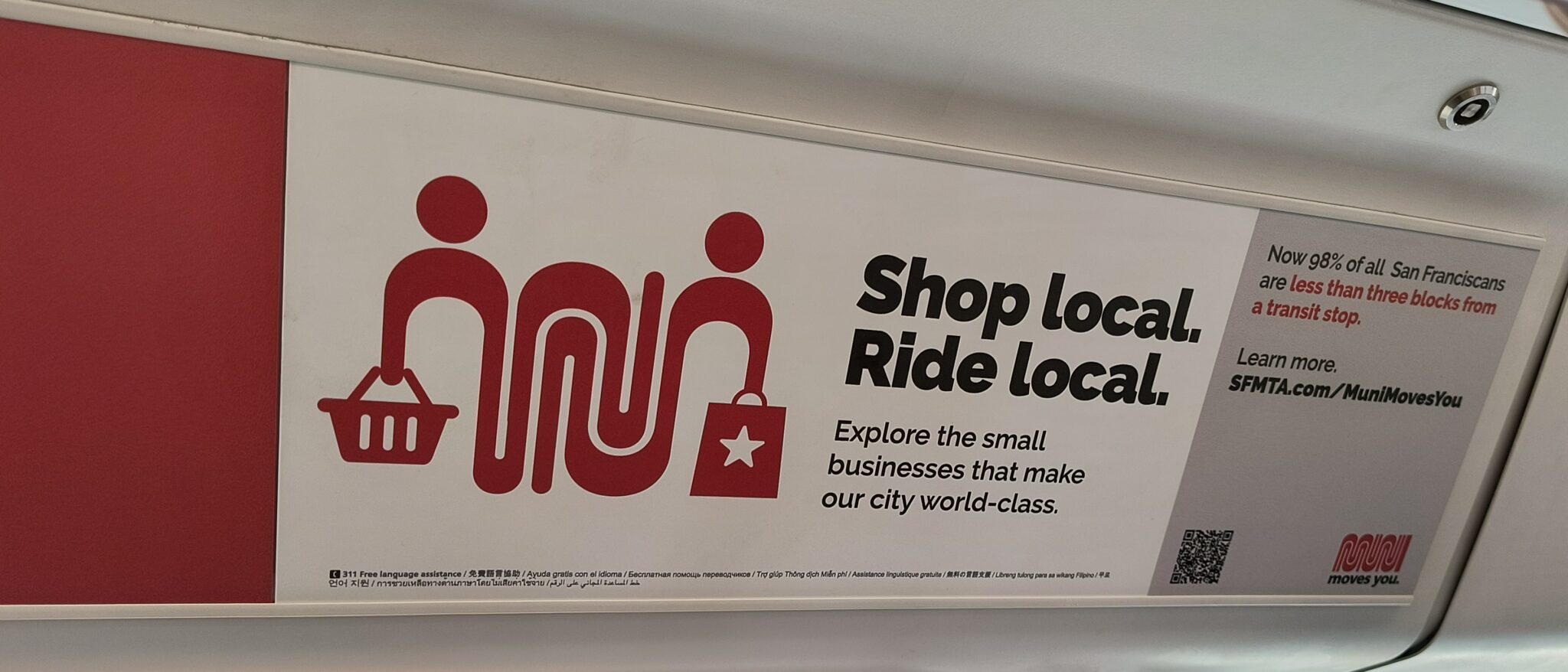 Ad on train with Muni logo stylized as two people holding bags. Text reads: Shop local. Ride local.